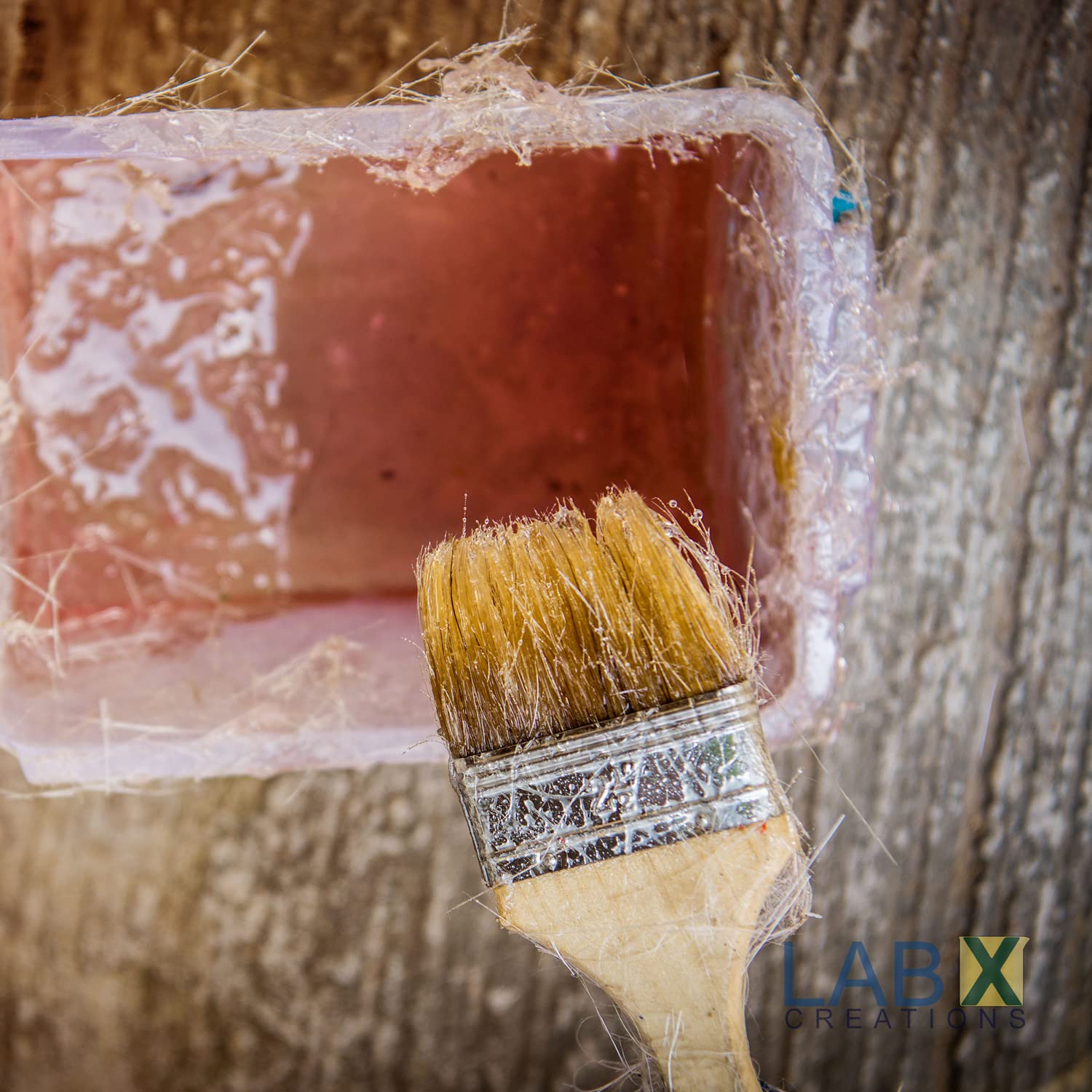 Paintbrush with wooden handle and metal ferrule, and a container with resin in it.