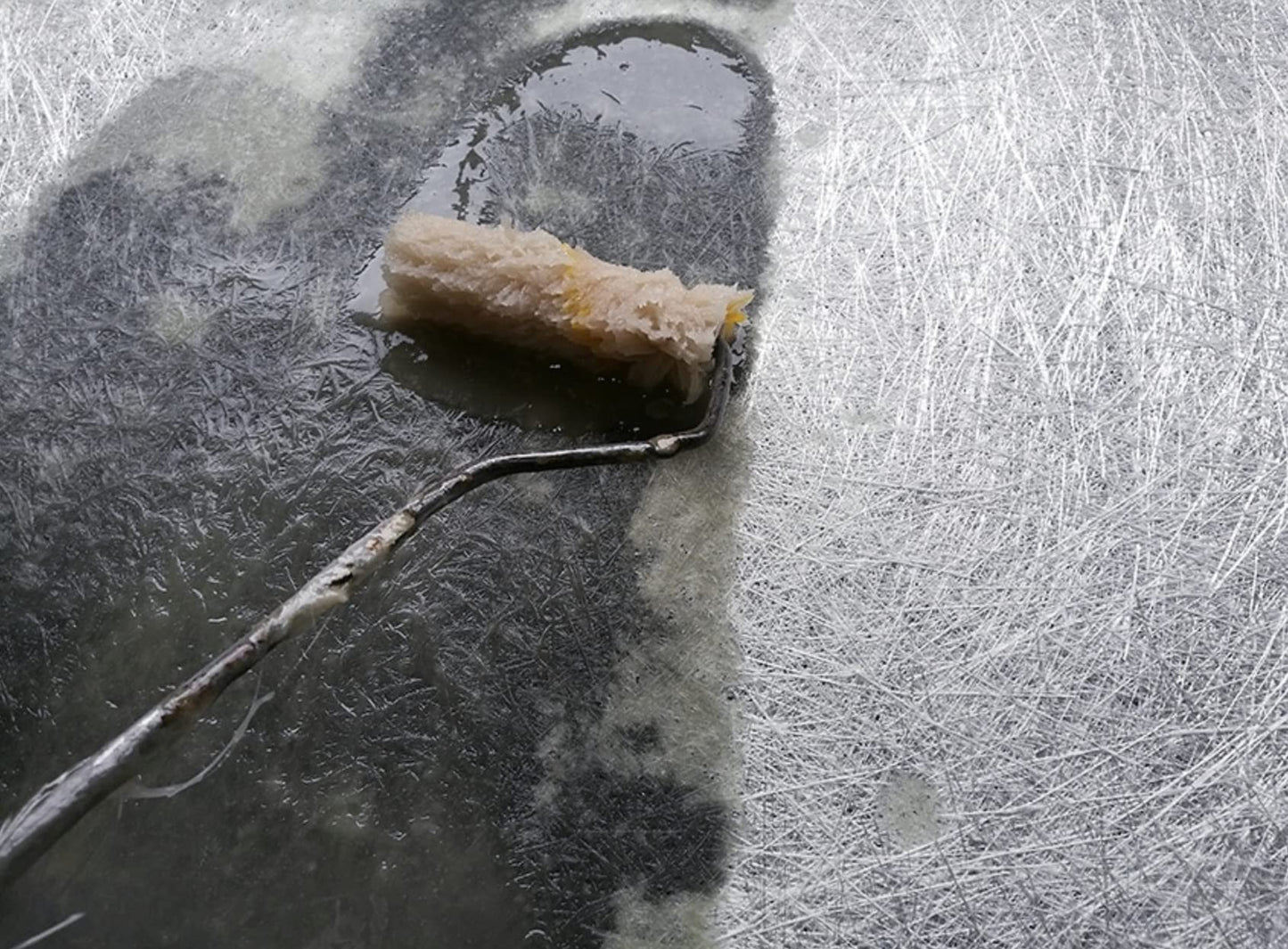 Roller with a textured roller sleeve applying resin to fiberglass