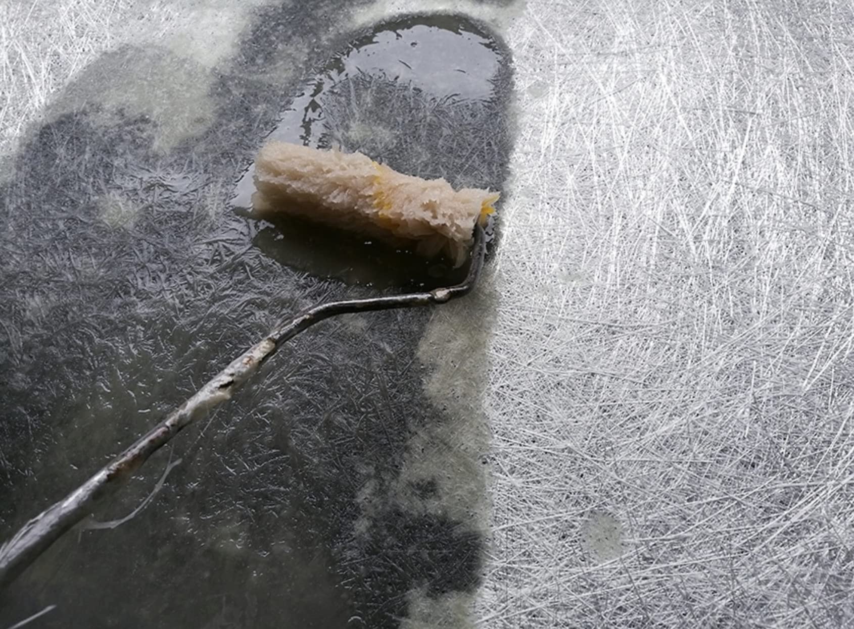 Roller with a textured roller sleeve applying resin to fiberglass